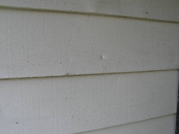 Debris impact marks from hurricane winds destroy Florida house siding